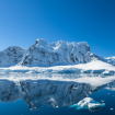 Winterlandschaft mit Bergen im Hintergrund. Im Vordergrund ein See