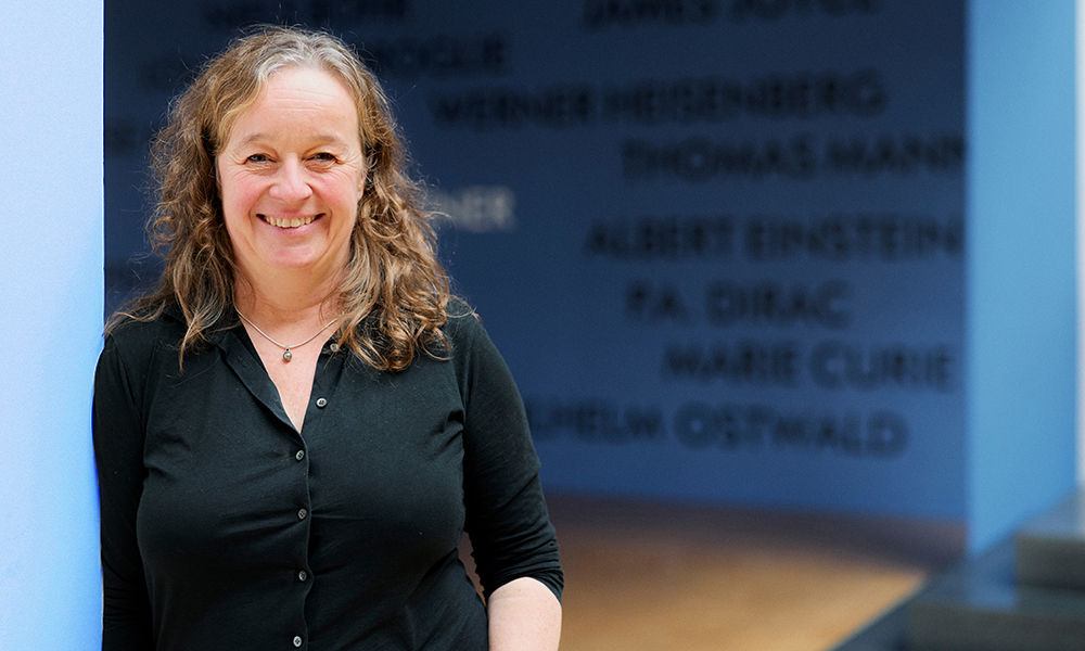 Portraitfoto von Gesine-Mollenhauer, lächelnd an eine Wand gelehnt