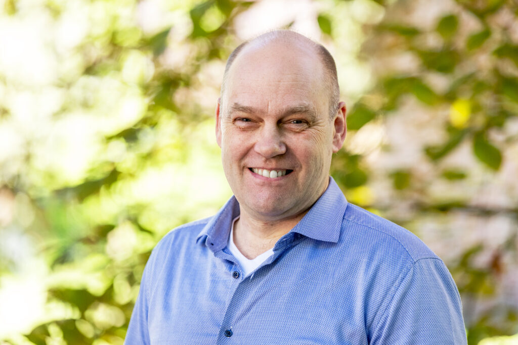 Portraitfoto von Henrik-Mouritsen, lächelnd vor einem grünen Hintergrund