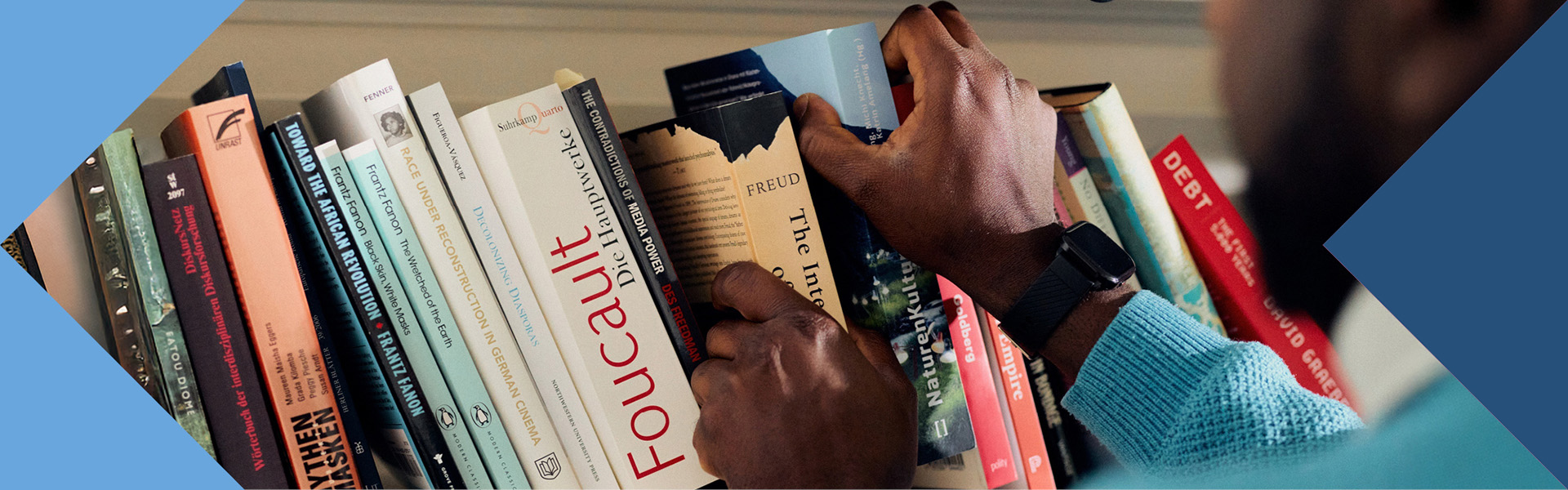 Wissenschaftliche Bücher werden von einer farbigen Person in ein Bücherregal einsortiert.