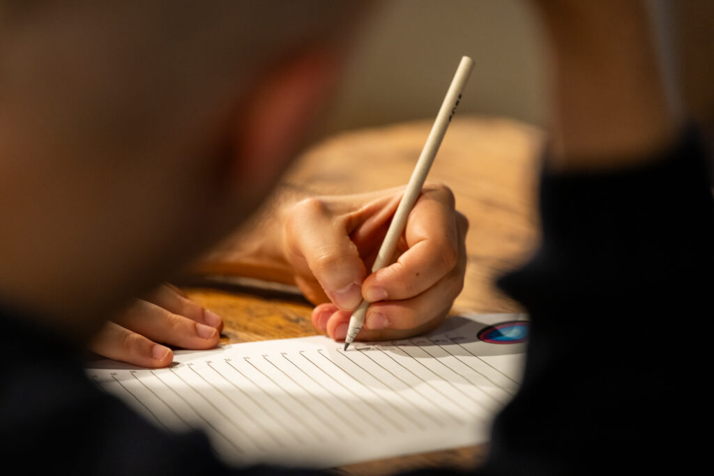 Eine Hand schreibt mit einem Bleistift.