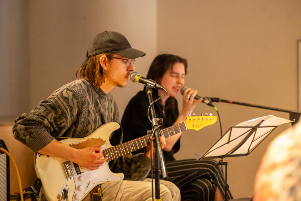 Zwei Menschen singen und spielen Gitarre.