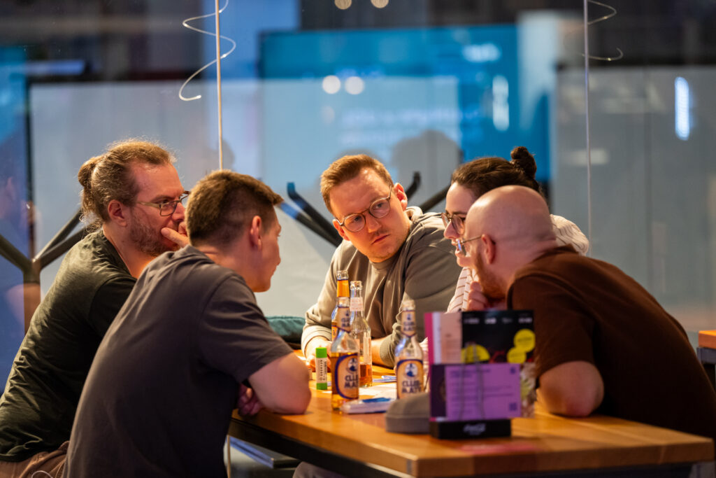 Fünf Menschen unterhalten sich am Tisch.