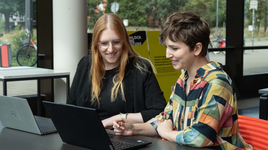 Nicola Thoben und Caroline Dominik schauen auf einen Laptop.